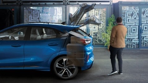 Ford Puma ST in Grau. Nahe Seitenansicht, ein Mann öffnet die sensorgesteuerte Heckklappe per Fußbewegung
