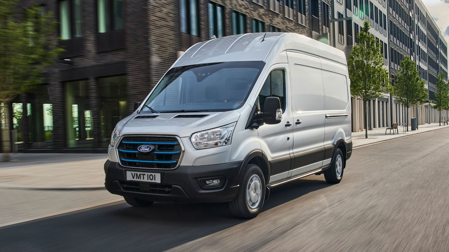 Ford E-Transit Kastenwagen Silber fährt auf Straße zur Arbeit