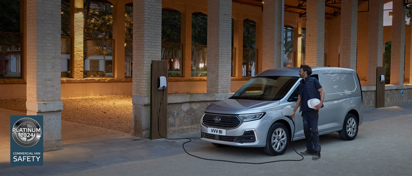 Ein Mann mit Schutzhelm steckt ein Wallbox-Ladekabel in einen Ford Transit Connect in Stardust-Silber.